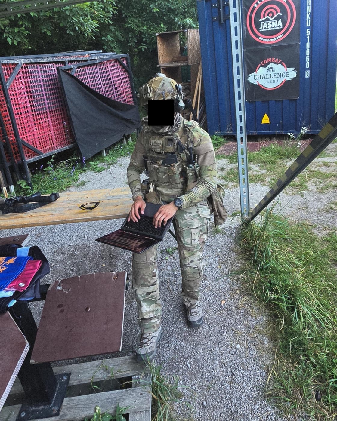 A Frontdesk Assistants member in kit working on a laptop at the range